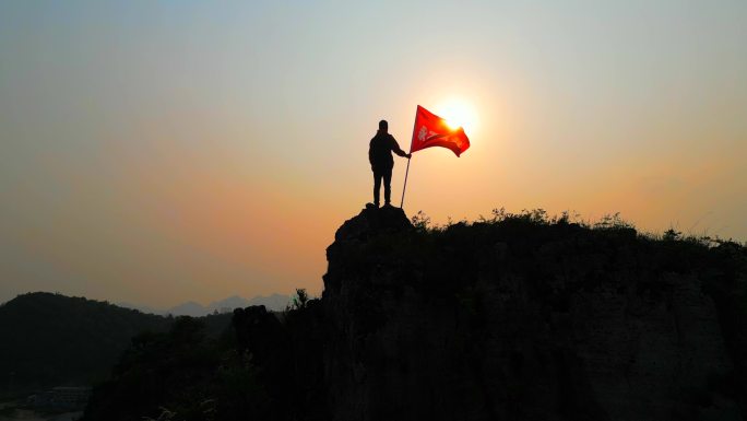 永不放弃登山者登顶山峰举起永不放弃的旗帜