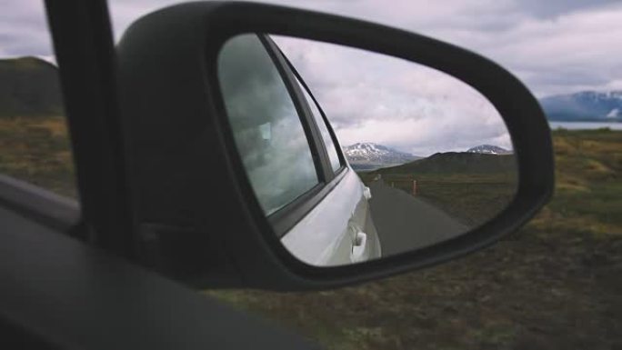 驾驶后视镜反映后方的行驶道路，背景为muontains