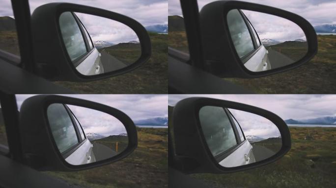 驾驶后视镜反映后方的行驶道路，背景为muontains