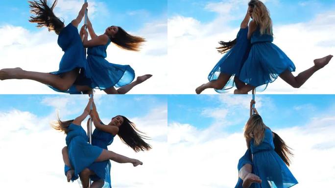 两个穿着蓝色裙子的女杂技演员在户外的蓝天下在塔尖上旋转