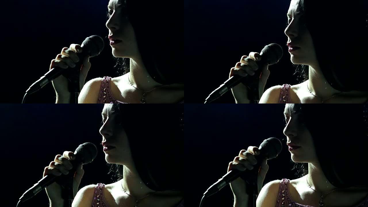 黑暗中带麦克风的女歌手剪影。
