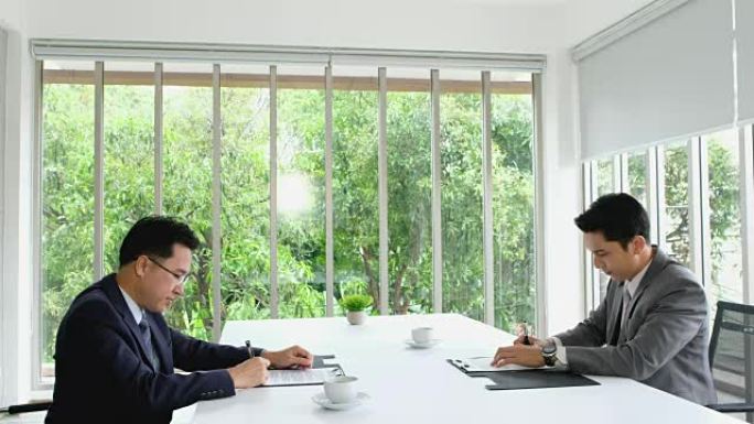 两名亚洲商人与商业交易签订合同并握手。伙伴关系概念。