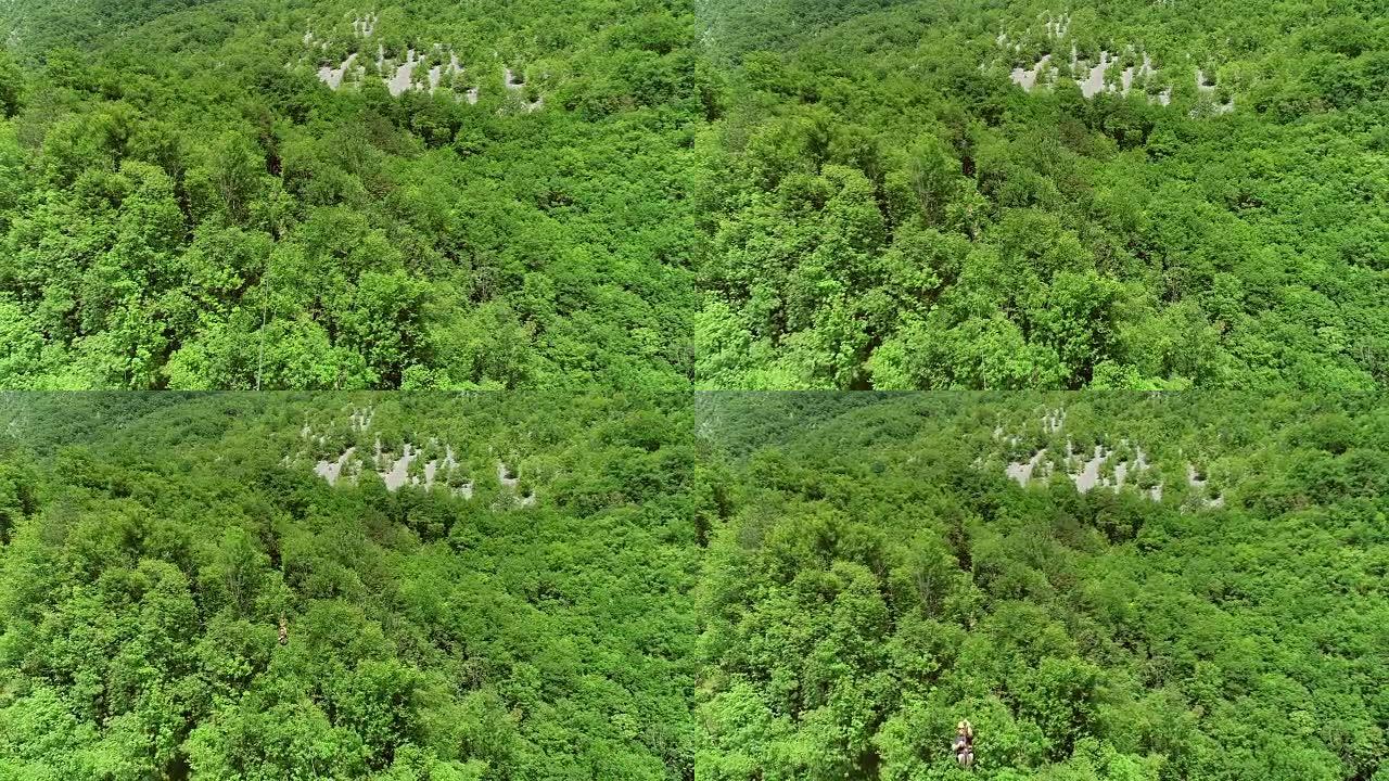 一个人通过一根大滑索穿过森林的鸟瞰图。