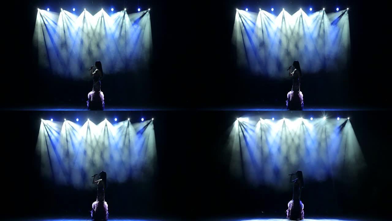 美丽的女孩在发光的舞台上唱歌。