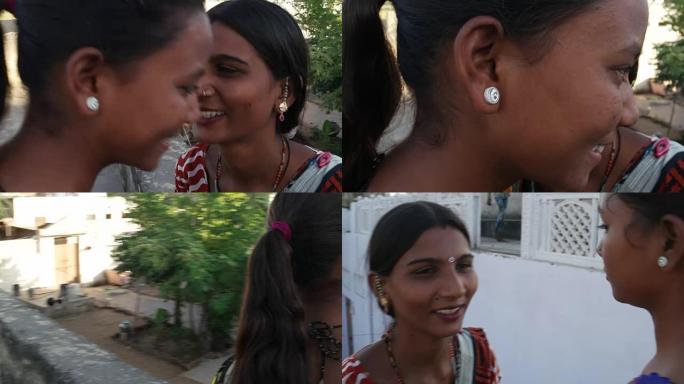 在夏季炎热的日子里，两位美丽的女士在印度农村的露台上分享和闲聊的手持特写镜头