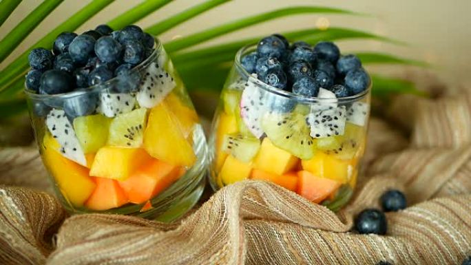 罐装彩色热带混合沙拉。玻璃碗中新鲜的各种生有机浆果和水果。健康素食主义者