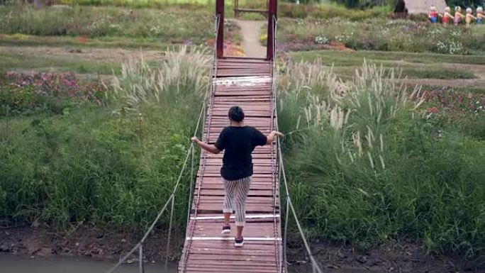 亚洲女性步行木吊桥公园