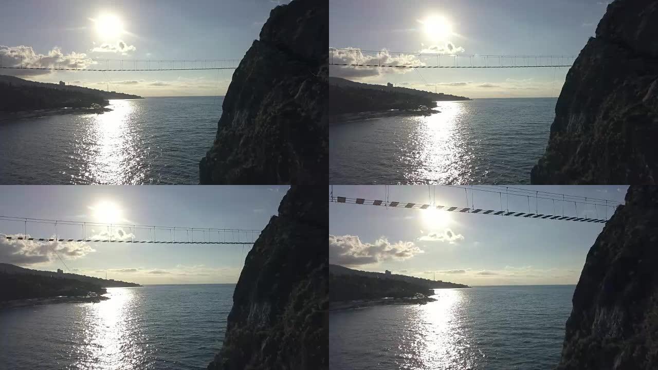 海上岩石与危险波浪和石头之间的绳索桥的鸟瞰图