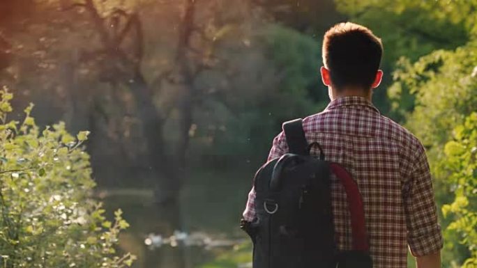 一个背着背包的少年走过公园，阳光照进镜头，美丽的眩光