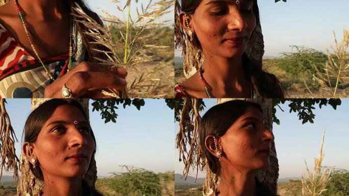 美丽的印度女士在树下等待情人考虑担心的想法，手里拿着蕨类植物烦躁紧张的秘密聚会地点日期户外夏季烈日阳