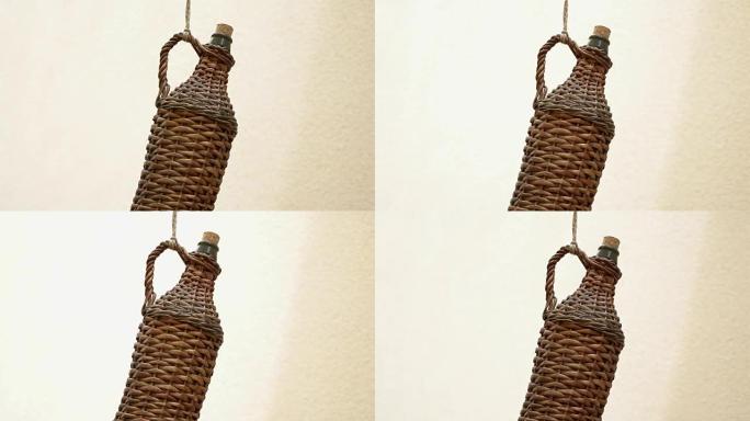 一个古老的，时尚的柳条酒瓶，挂在酒窖前的绳子上。
