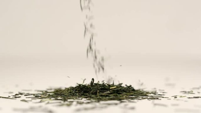 慢动作: 茶叶的微距镜头落在一堆绿茶上