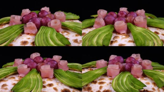 鳄梨，葡萄和装饰火腿的比萨饼，如玫瑰旋转