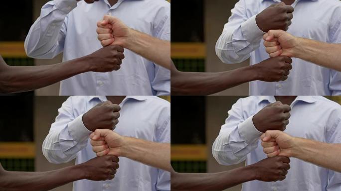 各国人民之间的团结。黑人和白人触摸的闭合拳头-慢动作
