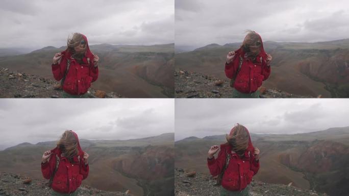 背着背包的女孩旅行者在恶劣的天气中挣扎。年轻女子游客在山里大雨下行走。