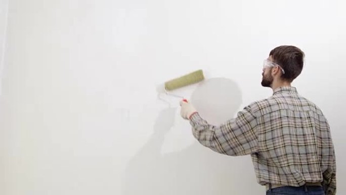 画家在工作，用滚筒粉刷墙壁，画家房子的概念