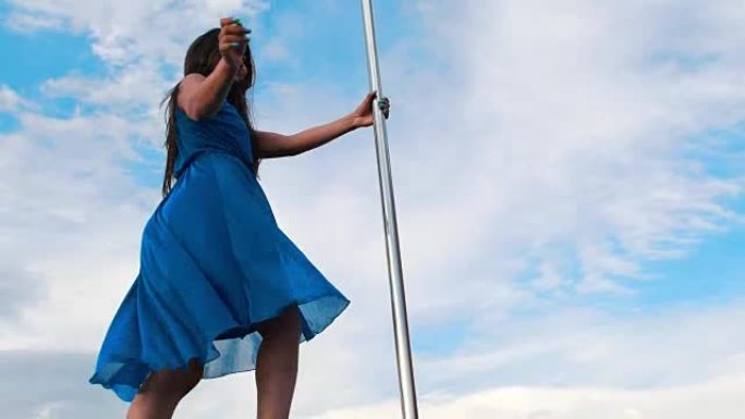 穿着蓝色连衣裙的迷人女人在天空表演钢管舞
