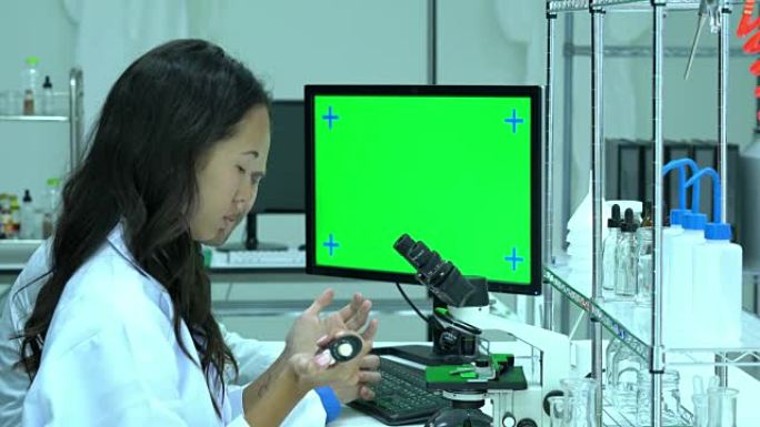 在现代实验室或医学中心工作的科学家。背景监视器绿色屏幕。科学、测试开发和实验室行业的概念。