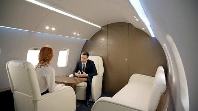 年轻的商人坐在私人飞机上讨论现代商业