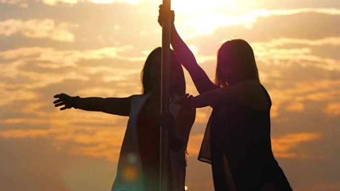 两名灵活女性的剪影在日落时表演钢管舞