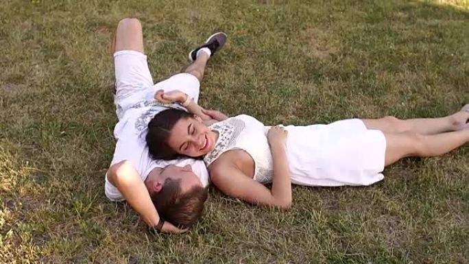 美丽的夫妇躺在公园的草地上。