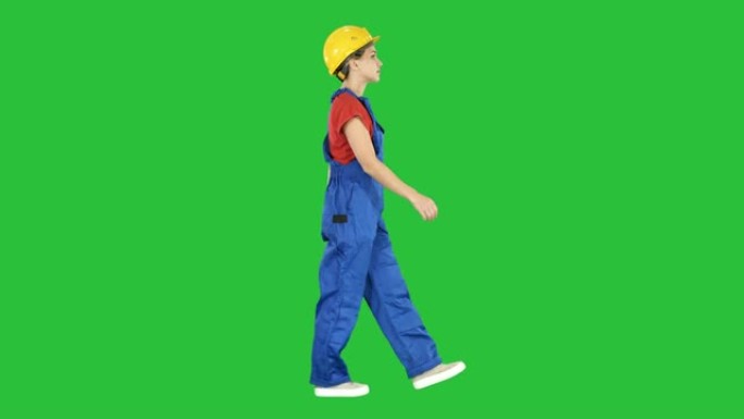 穿着黄色安全帽的年轻女性建筑工人走在绿色屏幕上，色键