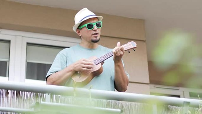 一位开朗的艺术家在夏天在阳台上演奏夏威夷四弦琴。