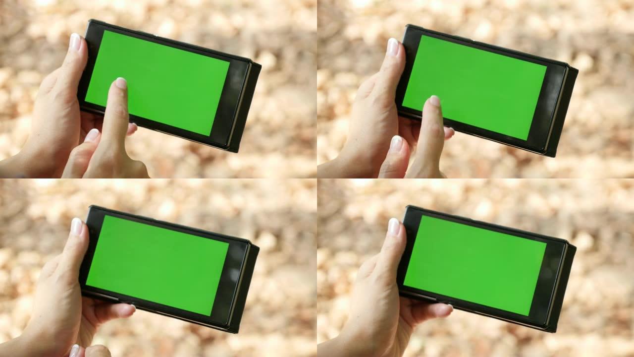 女人在自然4K中使用绿屏智能手机显示屏