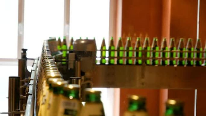 大量装有啤酒的玻璃瓶正沿着传送带移动。酒精产量低。饮料就可以吃了。工厂设备在工作。成品进入另一个阶段