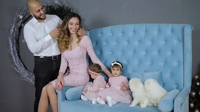 家庭田园诗，幸福的夫妇和孩子们在蓝色沙发上与两只小狗合影留念