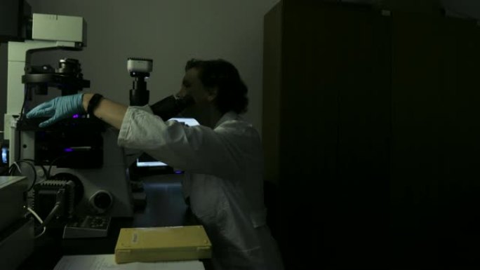 女性研究人员用荧光显微镜分析荧光染料标记的细胞样品