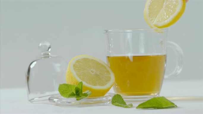 凉茶倒入透明茶壶，柠檬和薄荷叶周围，75 fps慢动作