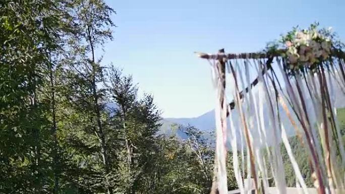 带丝带和鲜花的木结婚礼拱门。背景森林和山脉