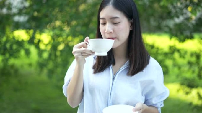 女人享受早晨的咖啡快乐，早上在家喝一杯咖啡，在阳光下呼吸新鲜空气