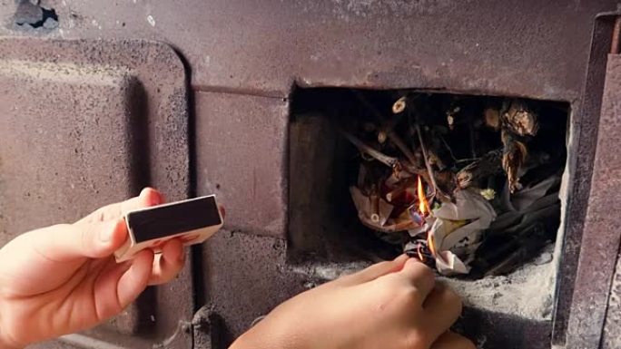 烧木头的炉子，一个孩子用火柴生火，在旧烤箱里刷木头，特写