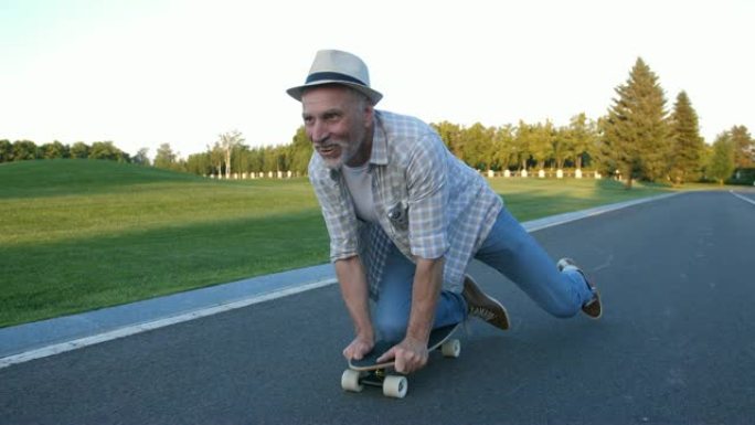 开朗的老人在公园的膝盖上滑板