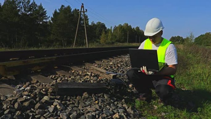 铁路附近的工程师用笔记本电脑检查电子继电器