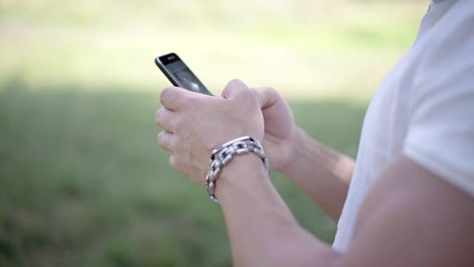年轻人在城市公园散步，使用智能手机观看新的互联网照片和视频
