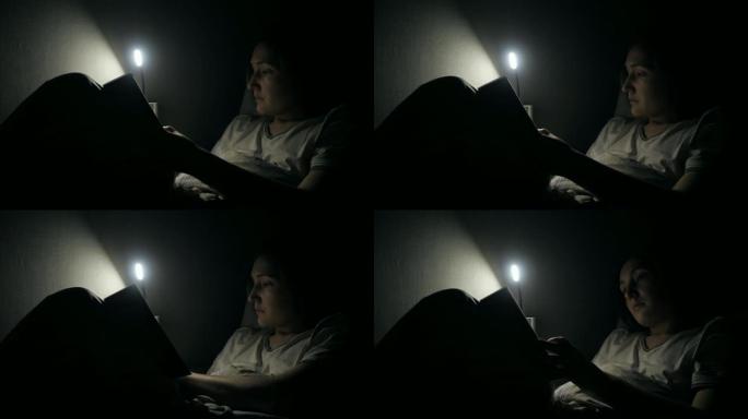 年轻女子晚上在床上看书