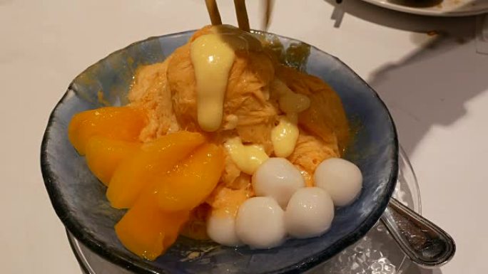 人们在泰国餐厅内将芒果糖浆倒在冰淇淋上的运动