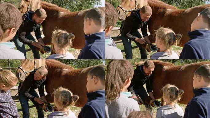 男子握着马的腿，向孩子们展示马蹄铁