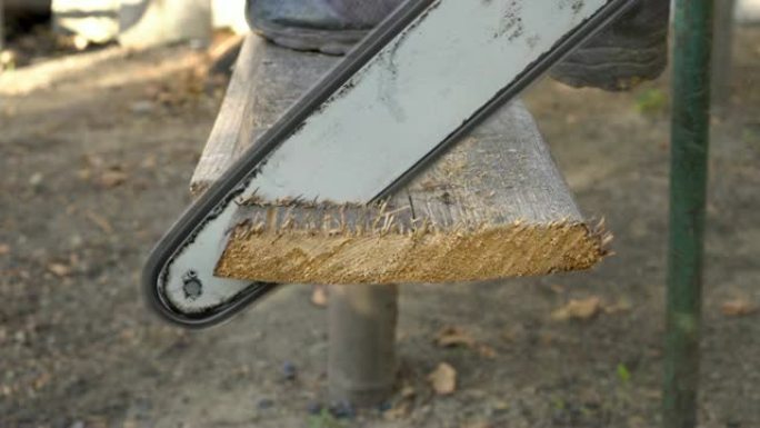 一个人用电锯锯掉一块旧木板，将脚放在上面。