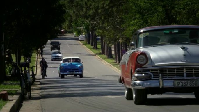 一排古老的经典美国20世纪50年代老式汽车在古巴的乡村小镇Vinales valley行驶