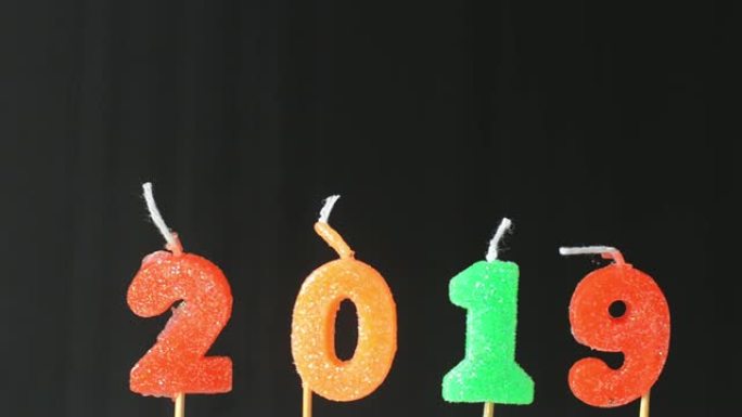 移动运动放大缩小视频新年快乐2019与闪光彩色闪光蜡烛数字黑色背景倒计时从年底和庆祝日欢迎来到新年。