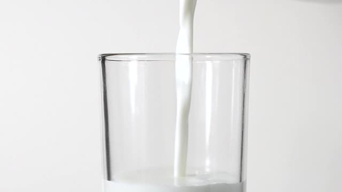 特写从白色背景的水罐中倒出新鲜牛奶
