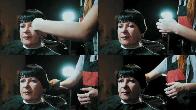 发型师在美发沙龙理发时剪掉女性头发。
