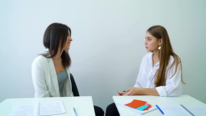 两名女高中生坐在教室里进行对话教程
