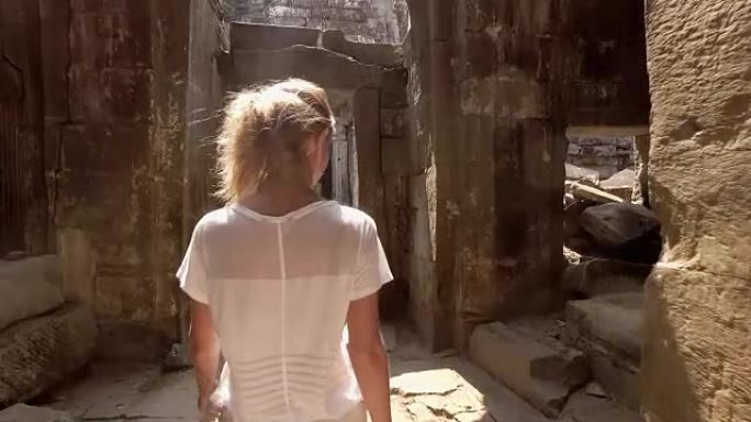 探索柬埔寨古代寺庙和文明的年轻女子在日落时走在古老的废墟中
