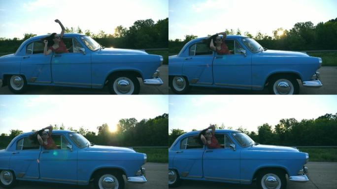 戴着太阳镜的迷人女孩从老式车窗外倾斜，享受旅行。年轻夫妇在夏天乘坐复古汽车旅行。旅游概念。背景阳光普