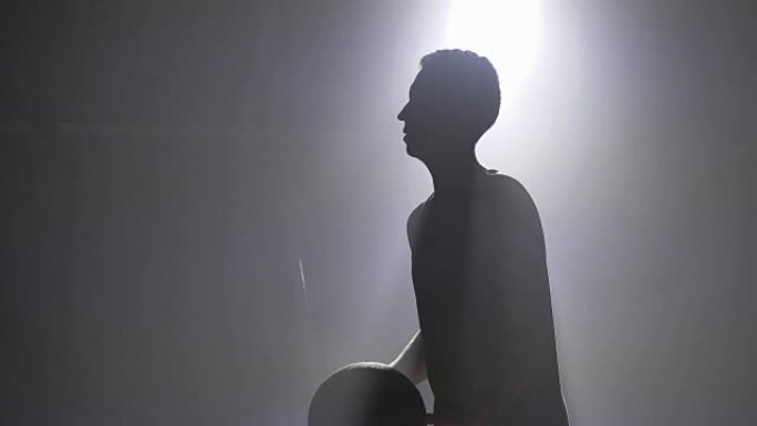 篮球运动员剪影练习灌篮和投球，背景为泛光灯